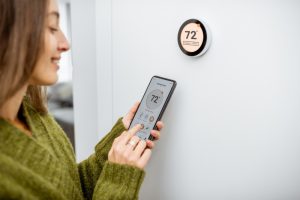 woman-adjusts-temperature-on-smart-thermostat-with-phone